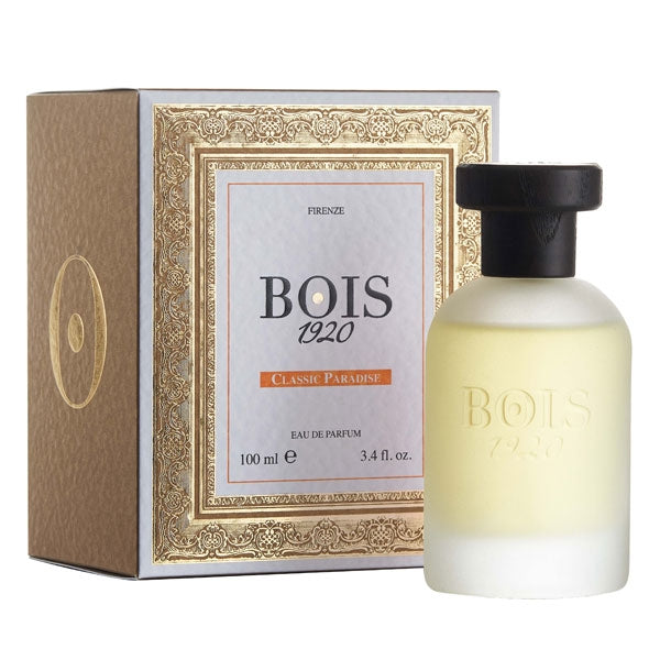 Bois 1920 - Classic Paradise Parfumflakon in mattiertem Glas mit schwarzem Verschluss neben edler goldverzierter Verpackung