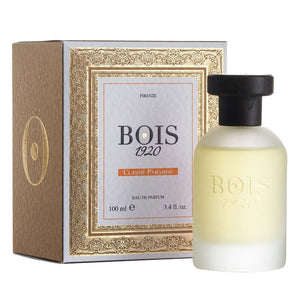 Bois 1920 - Classic Paradise Parfumflakon in mattiertem Glas mit schwarzem Verschluss neben edler goldverzierter Verpackung