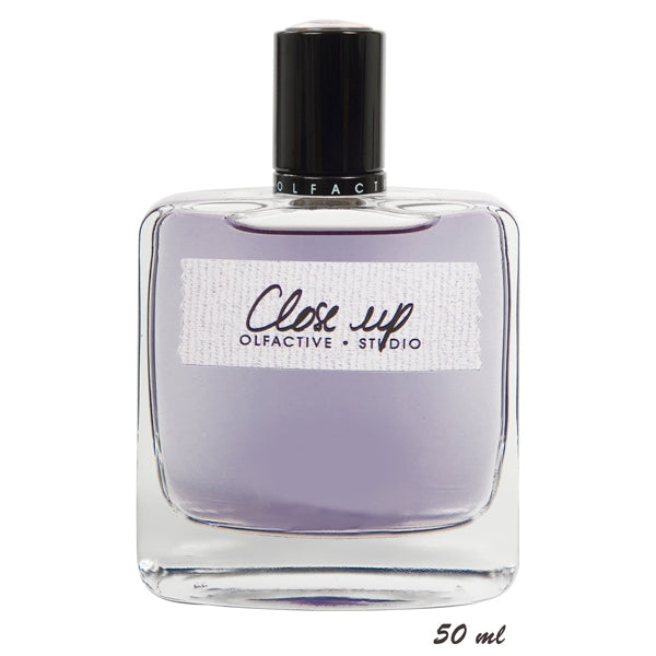 Olfactive Studio - Close Up Parfumflakon mit schwarzem Verschluss und leicht violettem Duft im klaren Glas vor weißem Hintergrund