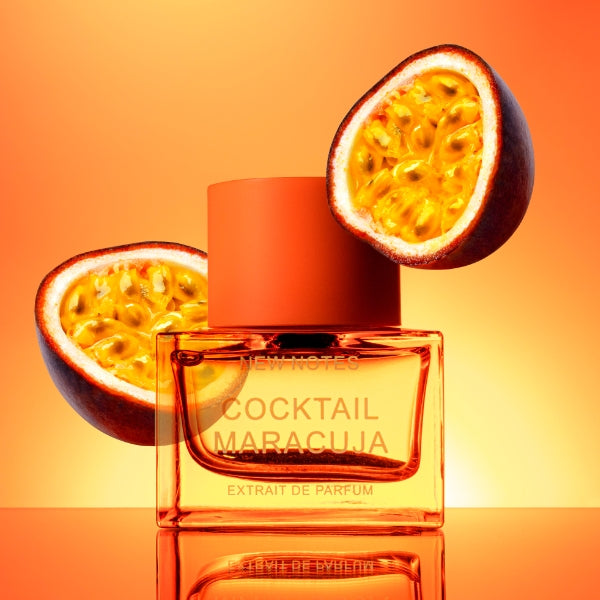 New Notes - Contemporary Blend Collection - Cocktail Maracuja mit orangefarbenem Flakon vor Passionsfruchthälften und warmem Hintergrund