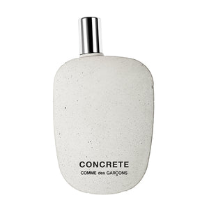 Comme des Garçons - Concrete Parfumflakon in unregelmäßiger Form mit Betonoptik und silbernem Sprühkopf vor weißem Hintergrund