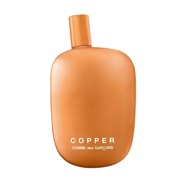 Comme des Garçons - Copper mattierter kupferfarbener Flakon mit geschwungener Form vor weißem Hintergrund