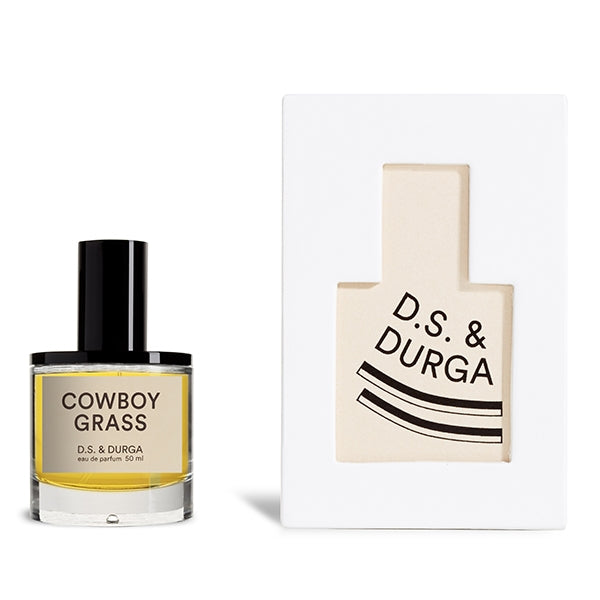 D.S. & Durga - Cowboy Grass Parfümflakon mit klarer Flasche und schwarzem Verschluss neben edler, weißer Verpackung
