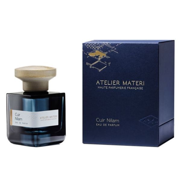 Atelier Materi - Cuir Nilam Parfumflakon in dunkelblauem Glas mit hellem Holzverschluss neben passender Verpackung