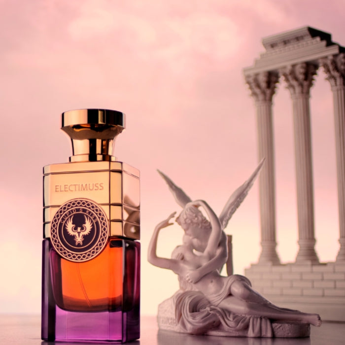 Electimuss - Cupid's Kiss Parfümflakon in elegantem Glas mit goldfarbener Kappe vor klassischer Engelsfigur