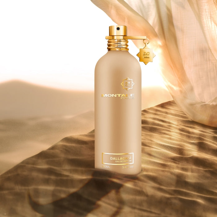 Montale - Dallachaï Flakon in goldener Optik mit elegantem Verschluss auf sandigem Untergrund bei Sonnenlicht