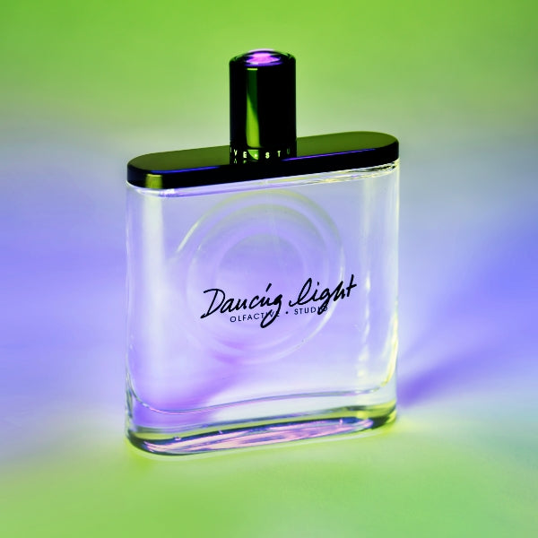 Olfactive Studio - Dancing Light Parfumflakon mit klarem Glas und schwarzem Verschluss vor farbigem Hintergrund