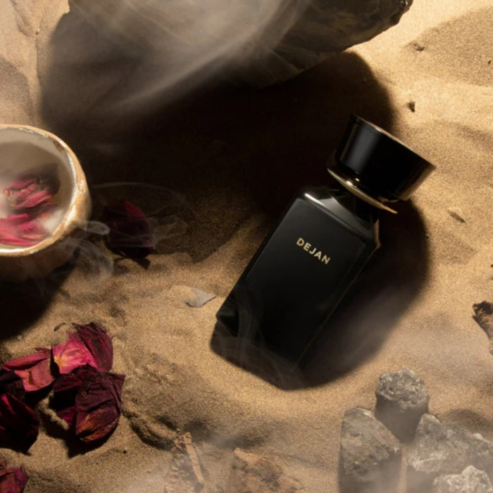 Omanluxury - Dejan - Limited Collection Parfümflakon in elegantem Schwarz auf sandigem Hintergrund mit Rosenblättern und Rauch