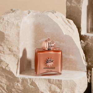 Amouage - Dia 40 Parfumflakon in kupferfarbenem Design auf natürlichem Steinpodest präsentiert