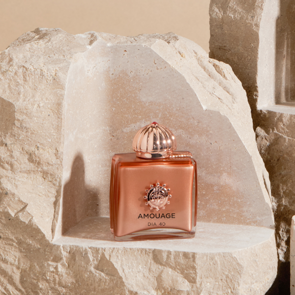 Amouage - Dia 40 Parfumflakon in kupferfarbenem Design auf natürlichem Steinpodest präsentiert