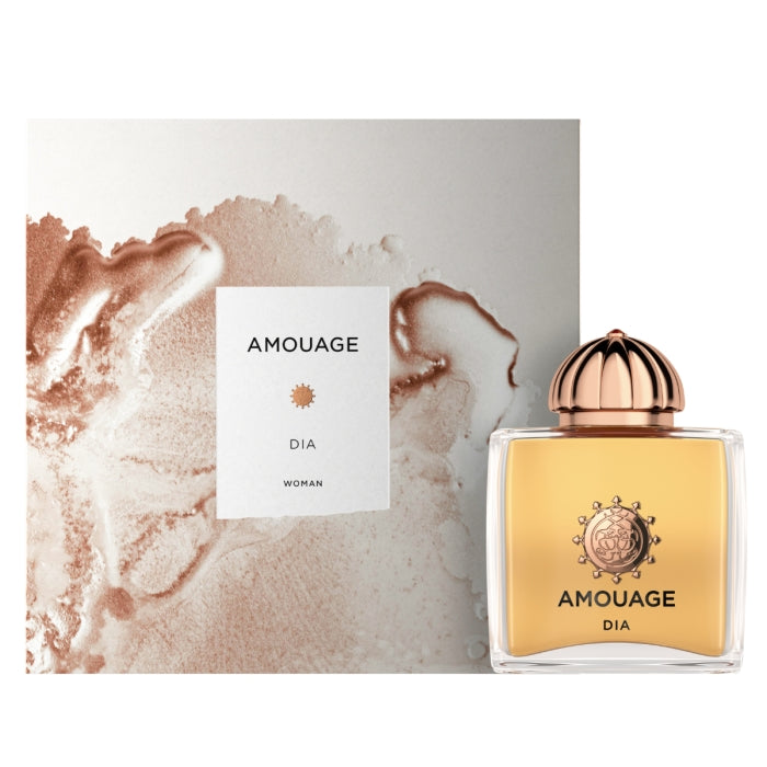 Amouage Dia Woman fragrance bottle with golden liquid and decorative rose gold cap beside artistic textured packaging on white background