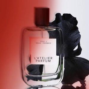 L'Atelier Parfum - Opus 1 - Douce Insomnie Flakon mit dunklem Holzverschluss vor samtigem schwarzem Blütenblatt und rotem Hintergrund