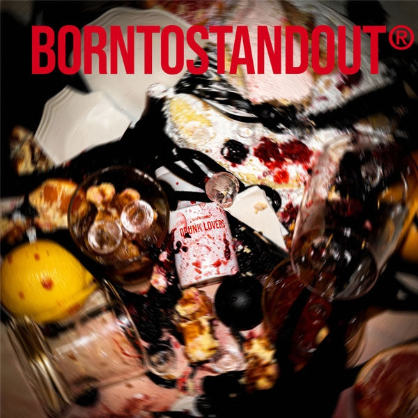 BORNTOSTANDOUT - Drunk Lovers Parfumflakon inmitten von zerbrochenem Glas und verschüttetem Brandy auf dunklem Holztisch