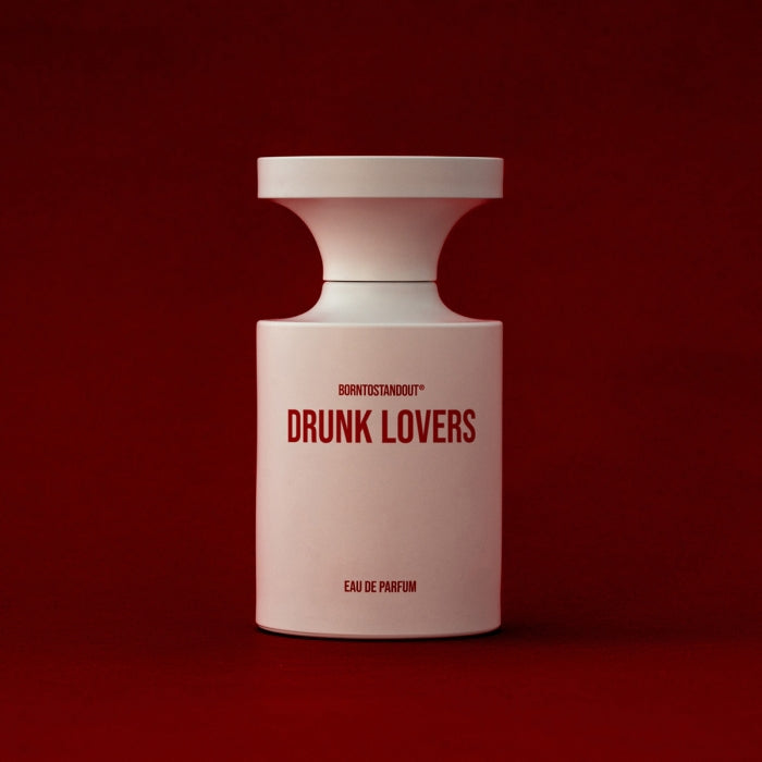 BORNTOSTANDOUT - Drunk Lovers Parfumflakon in mattem Weiß mit roter Schrift vor dunkelrotem Hintergrund