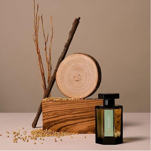 L'Artisan Parfumeur - La Collection - Il Était un Bois Parfümflakon neben Holzscheibe und Zweigen in natürlicher Szenerie