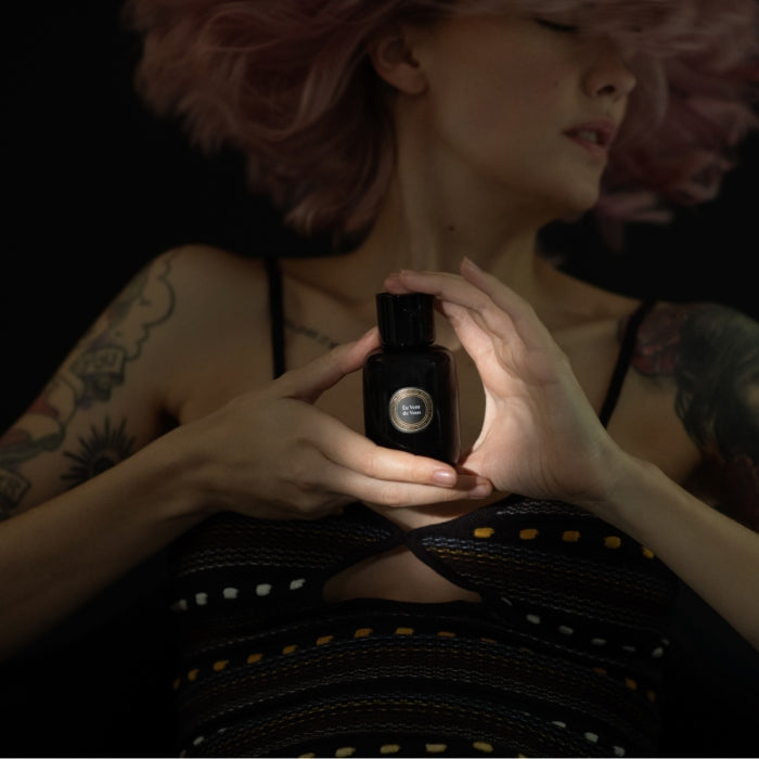 Sabé Masson - Eu Vent de Vous Flakon wird von Frau mit Tattoos vor dunklem Hintergrund inszeniert