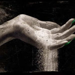 BeauFort London - Fathom V kreative Aufnahme einer Hand mit Sandkörnern vor dunklem Hintergrund