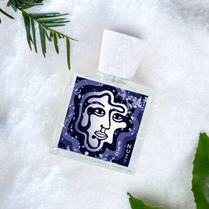 Carl Kling Parfums - Fig Nuit Flakon mit abstrakter Gesichtsgrafik auf dunklem Hintergrund liegt auf Schnee vor grünem Blatt
