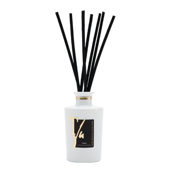 Teatro - Luxury Collection - Fiore - Diffusor präsentiert weißen Flakon mit goldener Schrift und schwarzen Diffusorstäbchen schlicht arrangiert