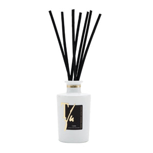 Teatro - Luxury Collection - Fiore - Diffusor präsentiert weißen Flakon mit goldener Schrift und schwarzen Diffusorstäbchen schlicht arrangiert