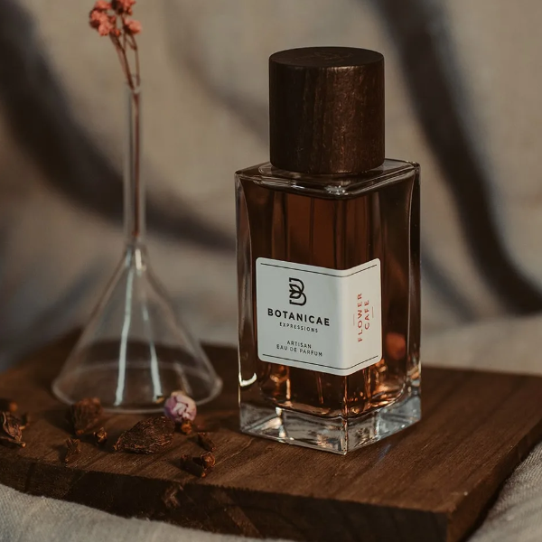 Botanicae - Flower Café Parfumflakon mit braunem Holzverschluss auf Holzbrett vor warmem, natürlichem Hintergrund