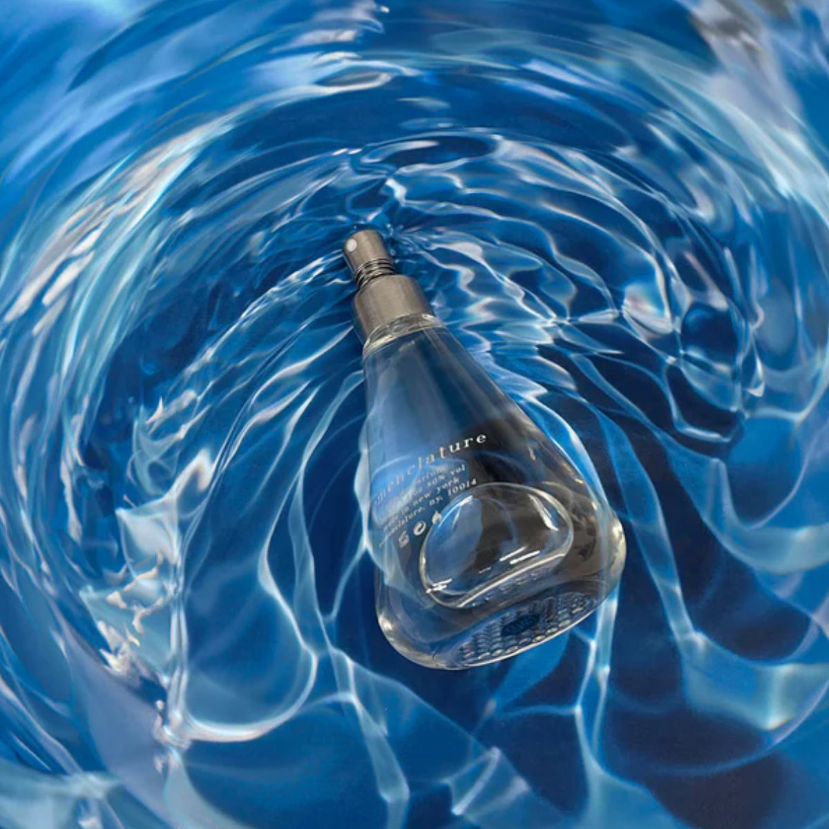 Nomenclature - fluo_ral Parfumflakon in tropfenförmigem Glas mit bläulichem Wasserreflexionseffekt