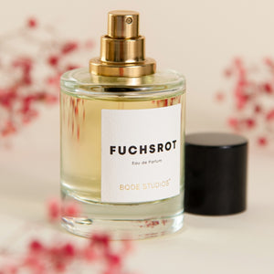 Bodé Studios - Fuchsrot Parfumflakon mit goldenem Zerstäuber und schlichtem Etikett vor hellem Hintergrund