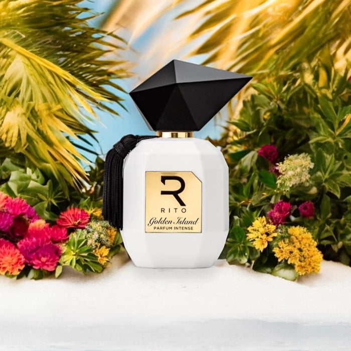 Rito - Golden Island Parfumflakon in weiß mit goldenem Label und schwarzem Facettendeckel vor buntem Blumenarrangement