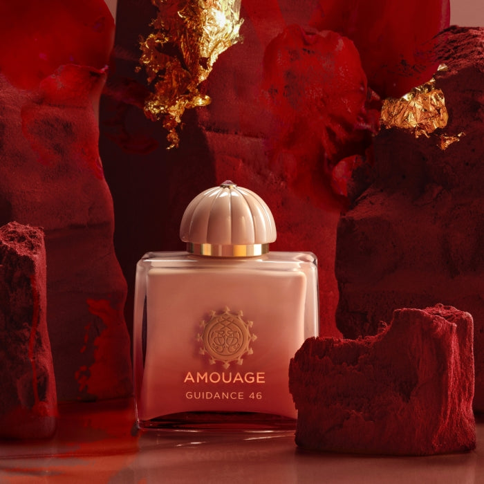 Amouage - Guidance 46 Parfümflakon mit goldener Kappe vor roter, strukturierter Kulisse und Goldakzenten