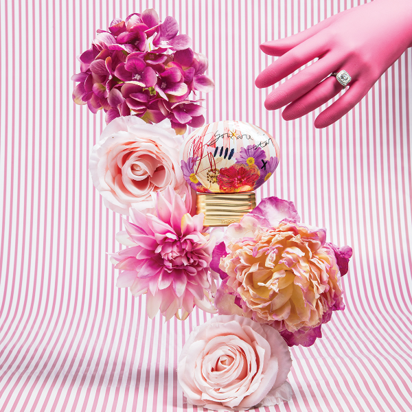 THoO - Crazy Collection - Guilty Crush Parfumflakon mit floralen Motiven und handschriftlichem Design auf goldenem Sockel vor gestreiftem Hintergrund