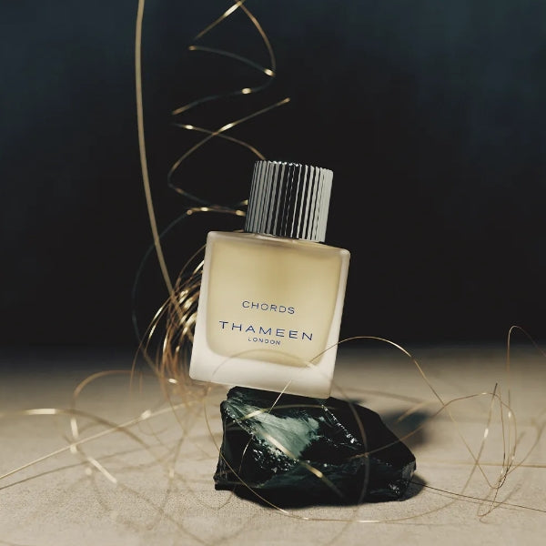 Thameen - Britologne Collection - Chords Parfumflakon mit matter Optik und geriffeltem Deckel auf dunklem Stein und goldenen Fäden
