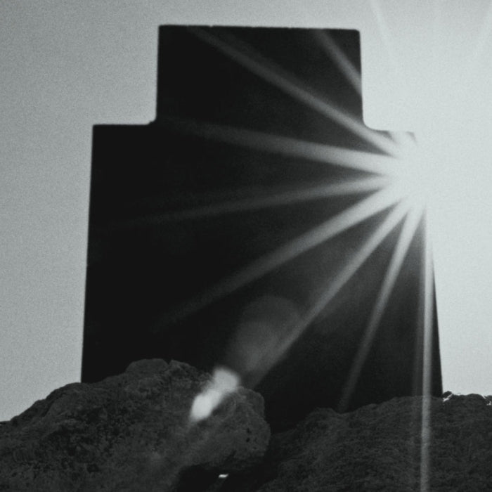 Rubini - Hyperion Parfumflakon-Silhouette mit strahlender Lichtquelle hinter dunkler Form auf felsigem Untergrund