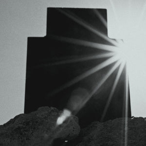 Rubini - Hyperion Parfumflakon-Silhouette mit strahlender Lichtquelle hinter dunkler Form auf felsigem Untergrund