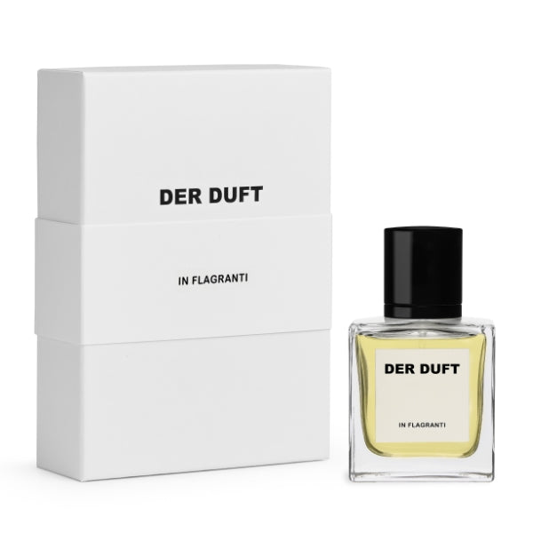 DER DUFT - In Flagranti Parfum in klarer Glasflasche mit schwarzem Verschluss neben weißer minimalistischer Verpackung