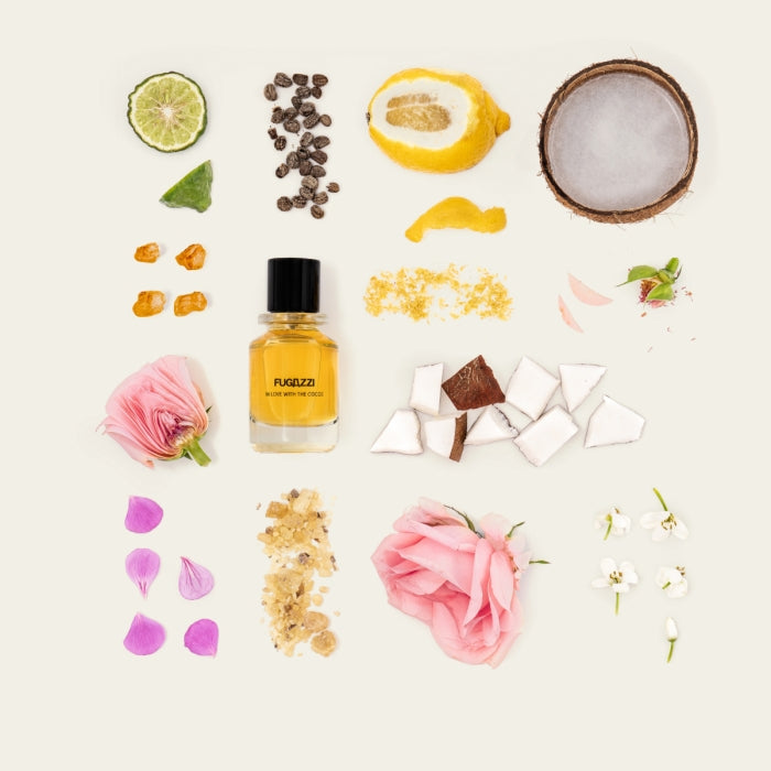 Fugazzi - In Love with the Cocos mit gelbem Duft umgeben von Kokosnuss, Zitrone, Blumen und Kaffeebohnen auf hellem Hintergrund