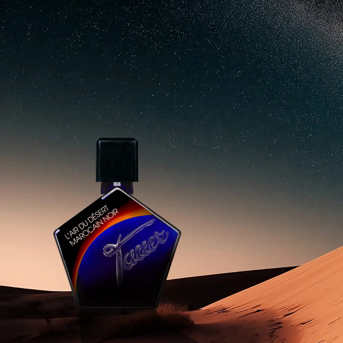 Andy Tauer - L'Air du Désert Marocain Noir - Elixir Flakon mit kantiger Form vor Sternenhimmel und Dünenlandschaft