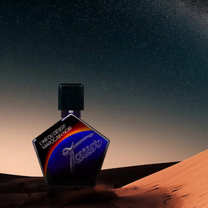 Andy Tauer - L'Air du Désert Marocain Noir - Elixir Flakon mit kantiger Form vor Sternenhimmel und Dünenlandschaft