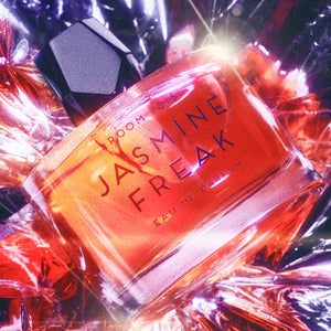 Room 1015 - Jasmine Freak Parfümflakon in leuchtendem Orange mit schwarzem Verschluss und reflektierendem Hintergrund