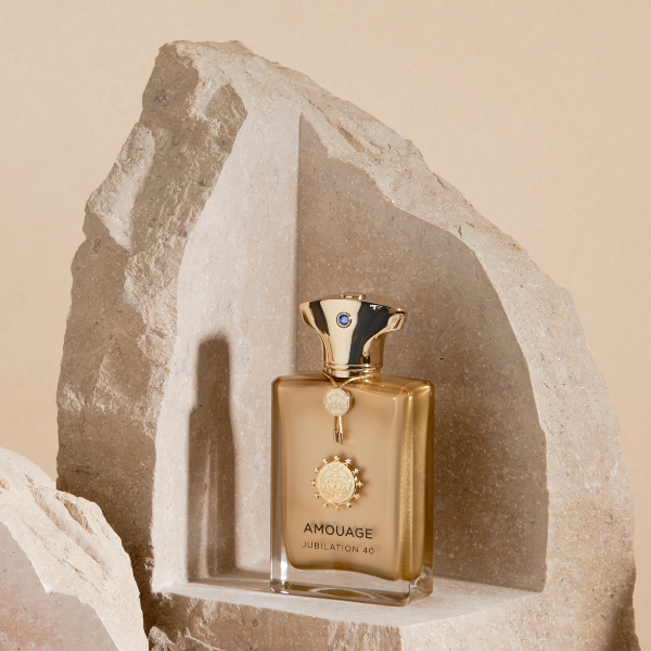 Amouage - Jubilation 40 elegant im goldfarbenen Flakon vor natürlichem Stein-Relief präsentiert