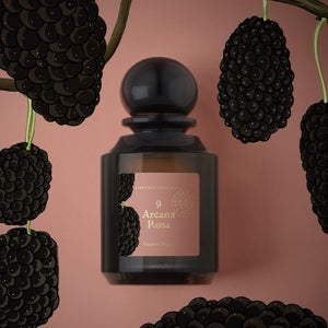 L'Artisan Parfumeur - La Botanique - Arcana Rosa Parfumflakon aus dunklem Glas mit Brombeerillustration auf rosafarbenem Hintergrund