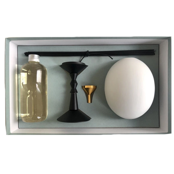 Trudon - L’Œuf Diffusor - Abd el Kader Set mit Duftöl, weißem Ei, Trichter und Duftstäbchen auf hellblauem Hintergrund