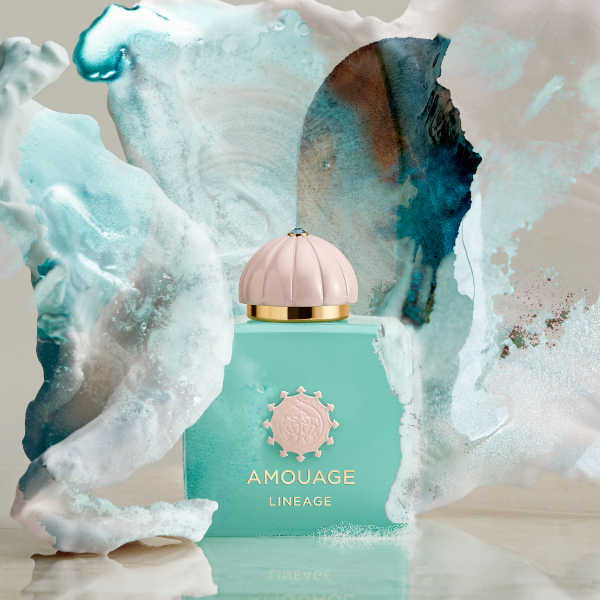 Amouage - Odyssey Collection - Lineage in mintgrünem Flakon mit pastellrosa Kappe vor abstraktem Hintergrund