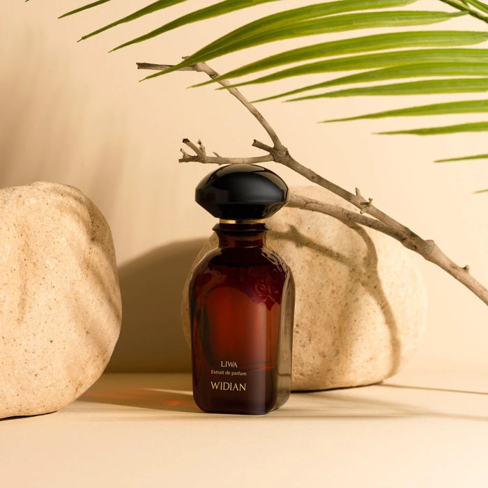 Widian - Velvet Collection - Liwa Parfumflakon in dunkelrotem Glas mit schwarzem Verschluss vor minimalistischer Steindeko