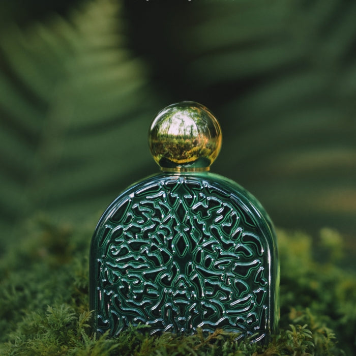 Micallef - The Secrets of Love Collection - Ma Nature Flakon mit grünem Reliefmuster und goldenem, rundem Verschluss vor Naturkulisse