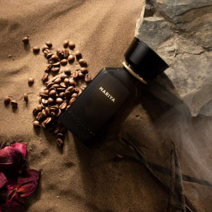Omanluxury - Mariya Parfümflakon in dunklem Glas, umgeben von Kaffeebohnen und Sand mit edlem Verschluss