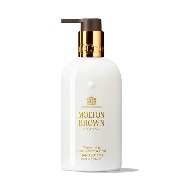 Molton Brown - Mesmerising Oudh Accord & Gold Hand Lotion weiße Flasche mit goldfarbenem Verschluss und braunem Pumpspender vor weißem Hintergrund