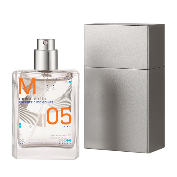 Escentric Molecules - Molecule 05 Travel Spray transparentes Flakon mit orangen Details neben silberner Reisehülle vor weißem Hintergrund