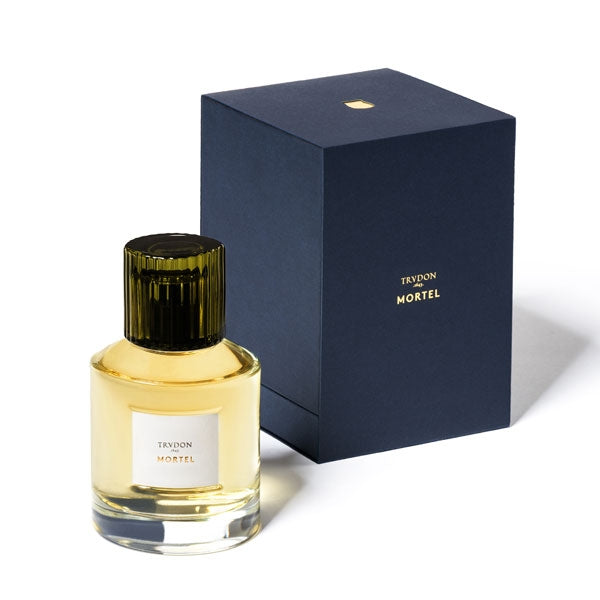 Trudon - Mortel Parfumflakon mit grün geriffeltem Verschluss und goldgelber Flüssigkeit neben dunkelblauer Verpackung