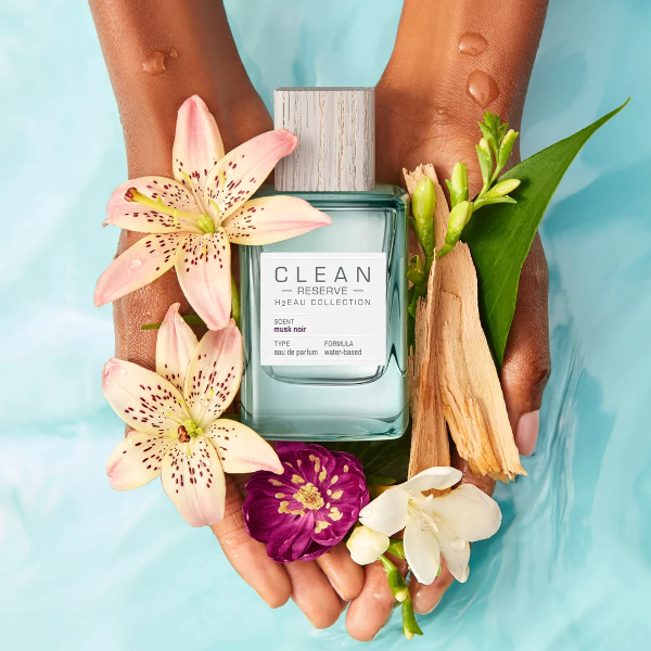 Clean Perfume - H2Eau Musk Noir Flakon in Händen mit Lilien, Veilchen und Holz vor hellem Hintergrund