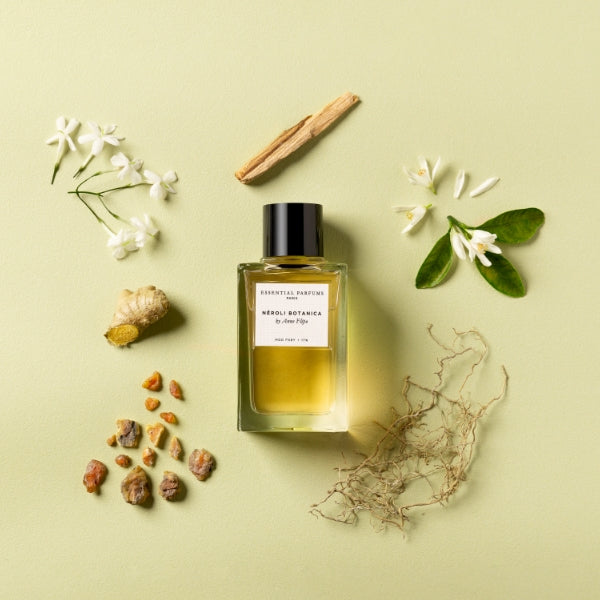 Essential Parfums - Néroli Botanica Flakon umgeben von natürlichen Zutaten auf hellem Hintergrund minimalistisch präsentiert
